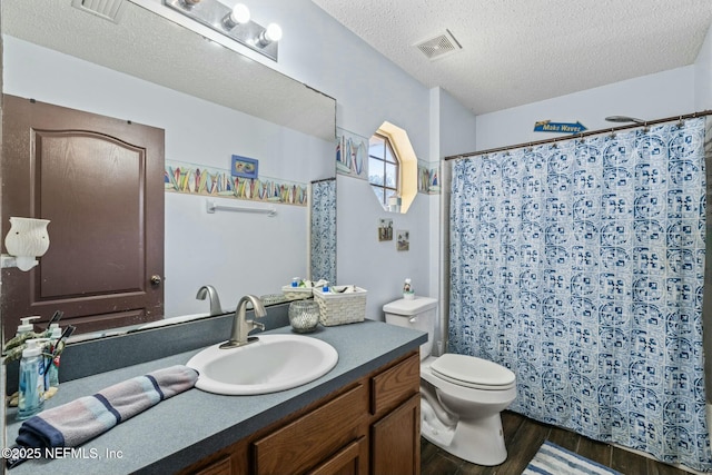 bathroom with toilet, vanity, hardwood / wood-style floors, a textured ceiling, and curtained shower