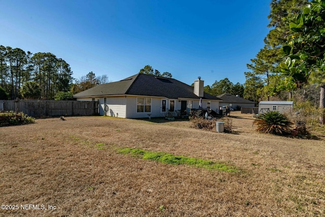 rear view of property with a lawn and a shed