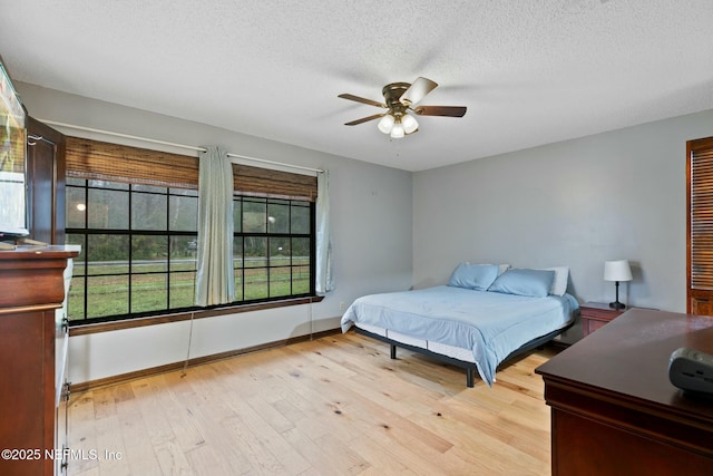 bedroom featuring light wood-type flooring, ceiling fan, and a textured ceiling