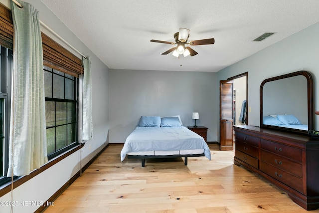 bedroom with ceiling fan, light hardwood / wood-style flooring, and a textured ceiling