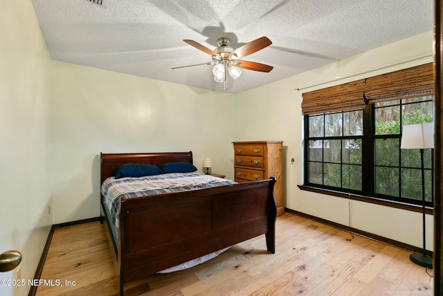 bedroom featuring ceiling fan, light wood-type flooring, and a textured ceiling