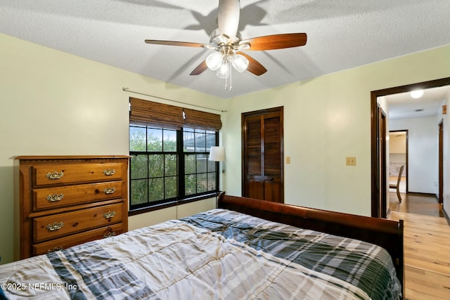 bedroom featuring ceiling fan, light hardwood / wood-style flooring, a closet, and a textured ceiling