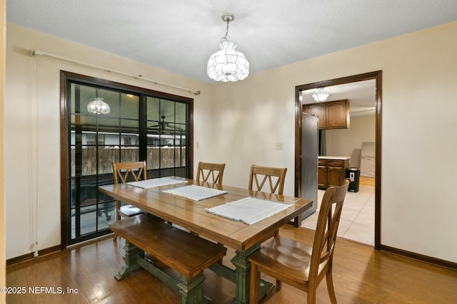 dining space with an inviting chandelier, light wood-type flooring, and a textured ceiling