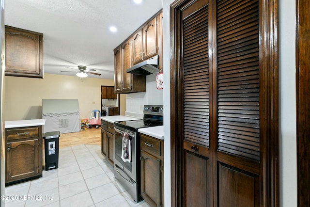 kitchen featuring electric range, light tile patterned floors, ceiling fan, a textured ceiling, and tasteful backsplash