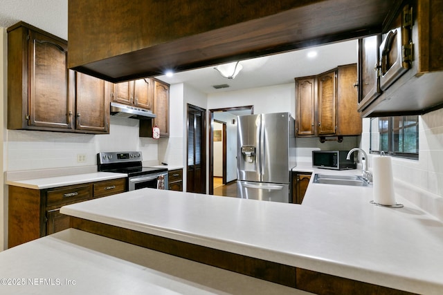 kitchen with sink, backsplash, kitchen peninsula, and appliances with stainless steel finishes