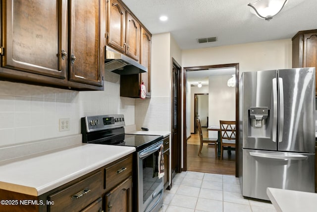 kitchen featuring appliances with stainless steel finishes, decorative backsplash, dark brown cabinetry, a textured ceiling, and light tile patterned flooring