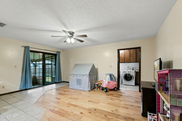 recreation room with ceiling fan, light hardwood / wood-style flooring, washer / clothes dryer, and a textured ceiling