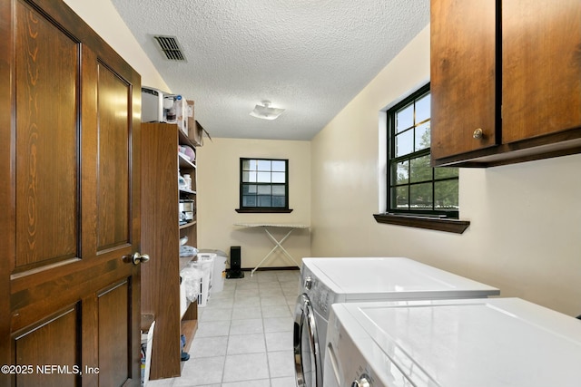 laundry room with separate washer and dryer, a healthy amount of sunlight, cabinets, and a textured ceiling