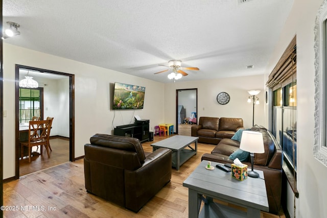 living room featuring a textured ceiling, ceiling fan, and wood-type flooring