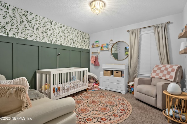 bedroom with carpet flooring, a textured ceiling, and a nursery area