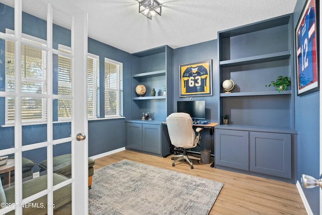 office with light hardwood / wood-style floors, built in desk, built in features, and a textured ceiling