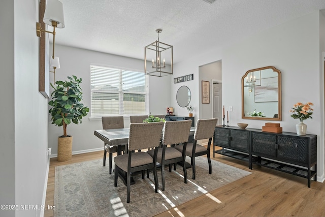 dining area featuring a chandelier, wood-type flooring, and a textured ceiling