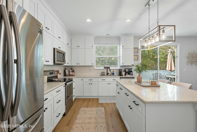 kitchen featuring appliances with stainless steel finishes, a center island, decorative light fixtures, and white cabinetry