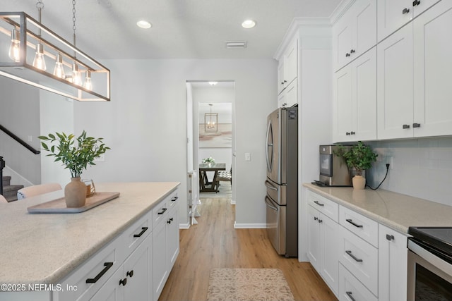 kitchen with white cabinets, hanging light fixtures, light hardwood / wood-style flooring, decorative backsplash, and stainless steel refrigerator