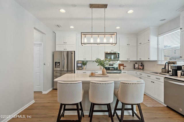 kitchen with sink, a center island, stainless steel appliances, and decorative light fixtures