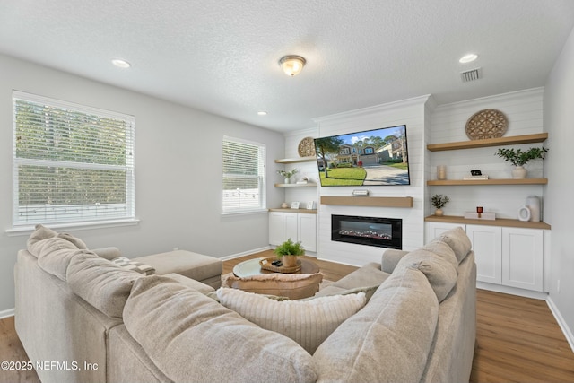 living room with a fireplace, a textured ceiling, and light wood-type flooring