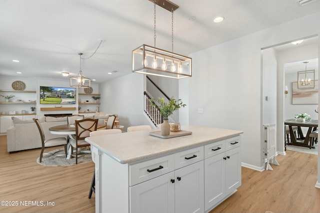 kitchen featuring a center island, white cabinetry, hanging light fixtures, and light hardwood / wood-style flooring