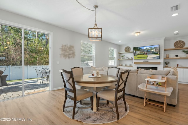 dining area featuring a large fireplace, a healthy amount of sunlight, and light hardwood / wood-style flooring