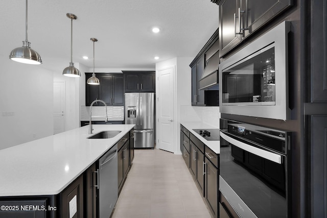 kitchen with sink, tasteful backsplash, decorative light fixtures, a center island with sink, and black appliances