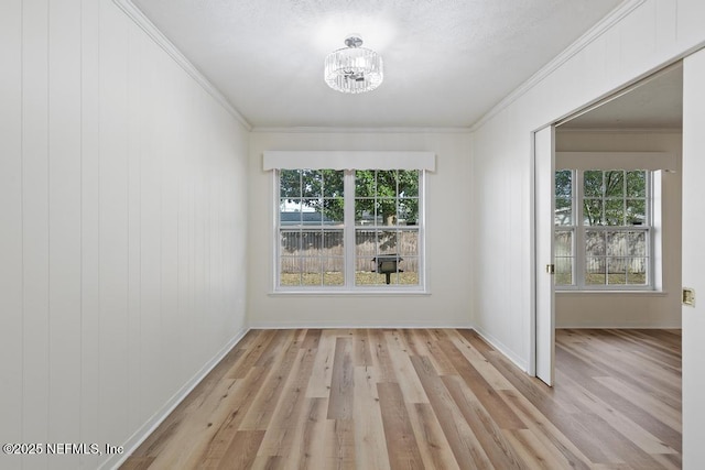 unfurnished room featuring a chandelier, light hardwood / wood-style floors, and ornamental molding