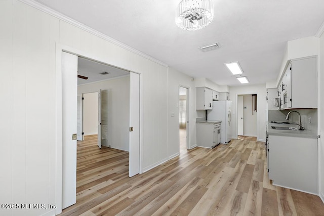 kitchen featuring white cabinets, light wood-type flooring, white fridge with ice dispenser, and sink