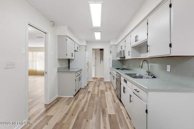 kitchen with sink, tasteful backsplash, white fridge, light hardwood / wood-style floors, and white cabinetry