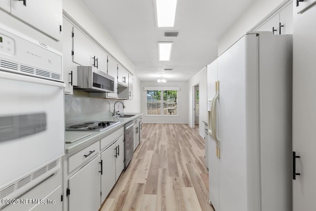 kitchen with sink, light hardwood / wood-style flooring, decorative backsplash, appliances with stainless steel finishes, and white cabinetry