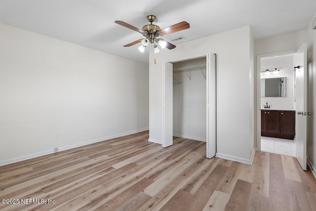 unfurnished bedroom with ceiling fan, ensuite bathroom, light hardwood / wood-style flooring, and a closet