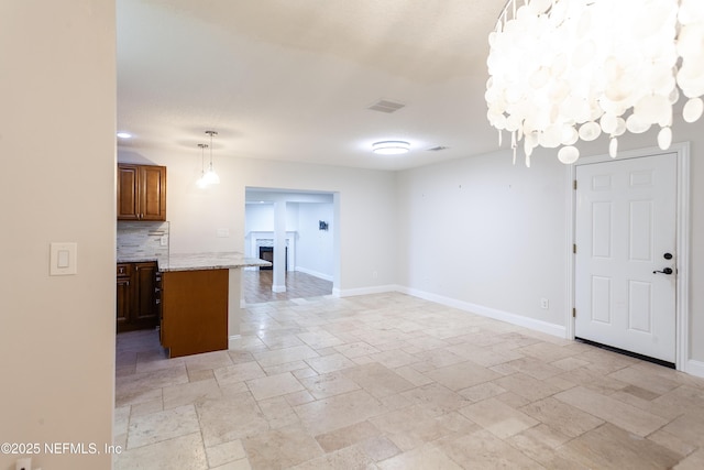 kitchen with decorative backsplash, pendant lighting, and light stone counters