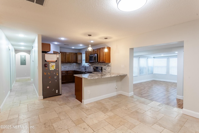 kitchen with hanging light fixtures, tasteful backsplash, kitchen peninsula, a breakfast bar, and appliances with stainless steel finishes