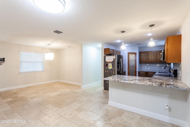 kitchen featuring stainless steel appliances, light stone counters, backsplash, kitchen peninsula, and pendant lighting