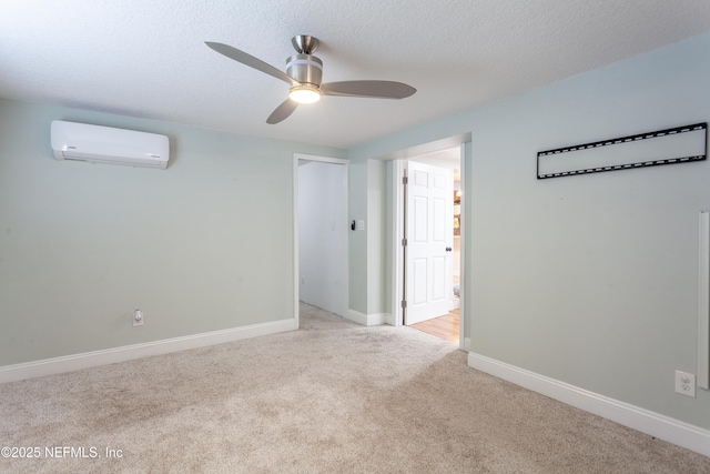 empty room with a textured ceiling, ceiling fan, light carpet, and a wall unit AC