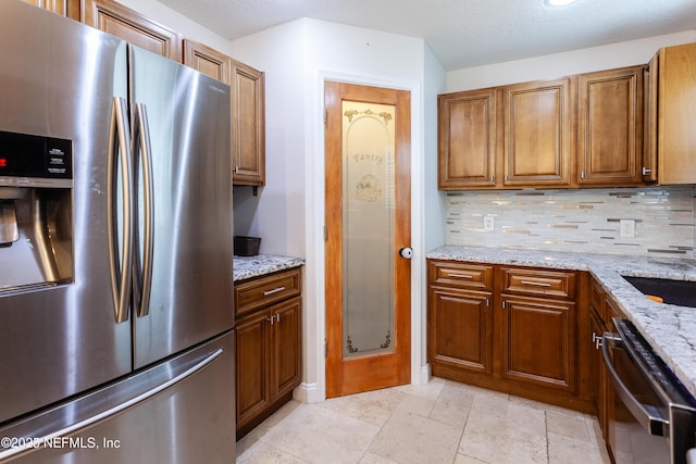 kitchen featuring decorative backsplash, light stone countertops, and appliances with stainless steel finishes