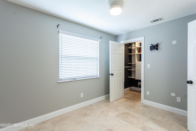 unfurnished bedroom featuring a walk in closet, a closet, and a textured ceiling