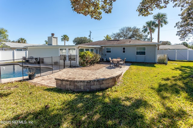 rear view of property featuring a lawn, a fenced in pool, and a patio