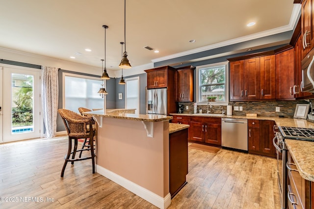 kitchen with a center island, hanging light fixtures, sink, a breakfast bar area, and stainless steel appliances