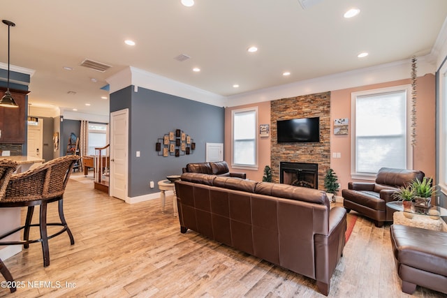 living room featuring a fireplace, crown molding, and light hardwood / wood-style floors