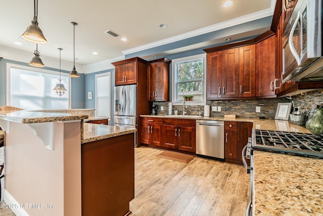 kitchen featuring light wood-type flooring, sink, appliances with stainless steel finishes, a breakfast bar area, and pendant lighting