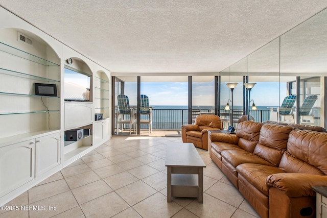 unfurnished living room with a textured ceiling, built in features, a wall of windows, and light tile patterned flooring