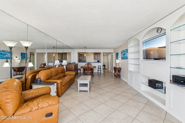 living room with built in features, light tile patterned flooring, and a textured ceiling