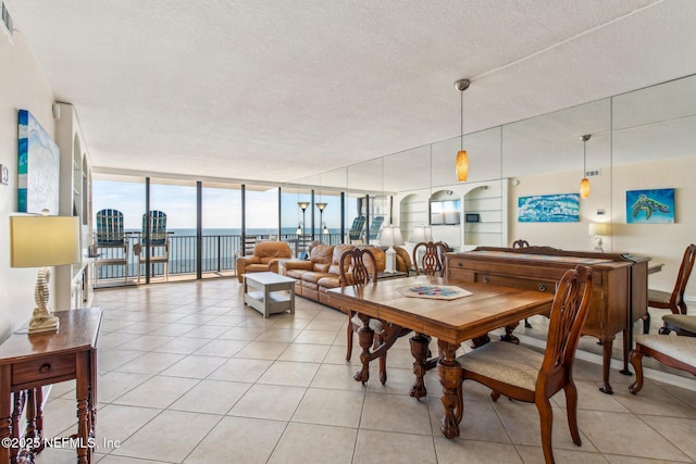 dining space featuring a water view, expansive windows, light tile patterned flooring, and a textured ceiling