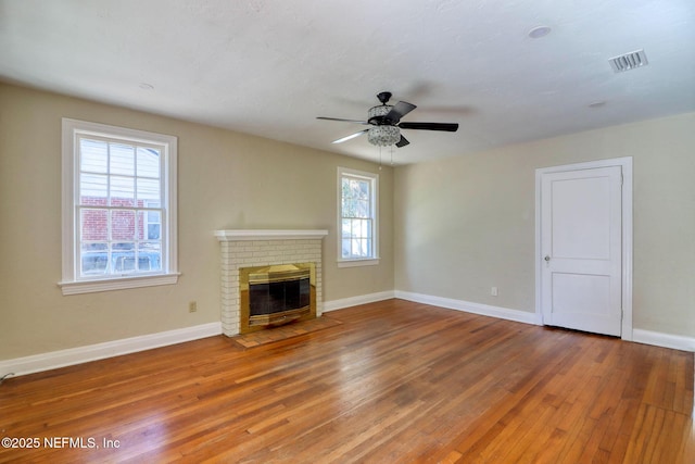 unfurnished living room featuring ceiling fan, a fireplace, and wood-type flooring