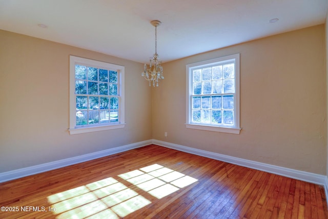 empty room featuring hardwood / wood-style floors and a notable chandelier