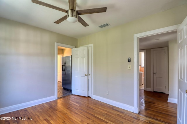 unfurnished bedroom featuring stainless steel fridge, ceiling fan, and dark hardwood / wood-style floors