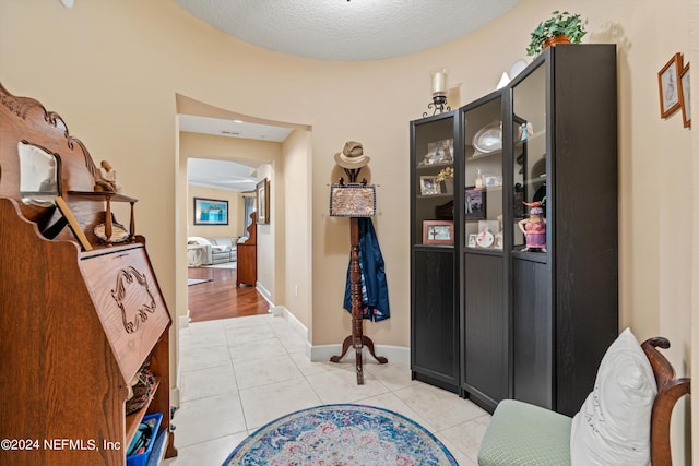 hall featuring light tile patterned floors and a textured ceiling