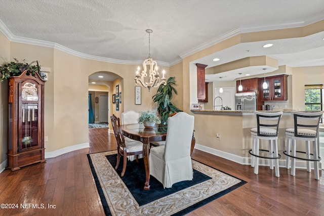 dining space with sink, an inviting chandelier, dark hardwood / wood-style floors, crown molding, and a textured ceiling