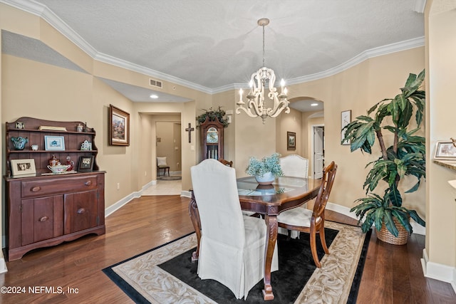 dining area with crown molding, wood-type flooring, a textured ceiling, and a chandelier