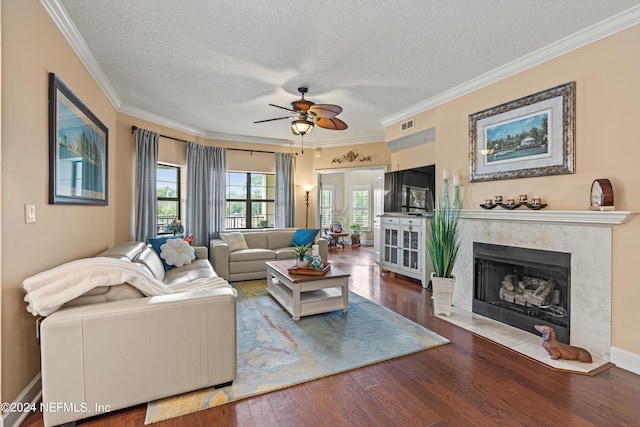 living room with a fireplace, a textured ceiling, ceiling fan, and ornamental molding