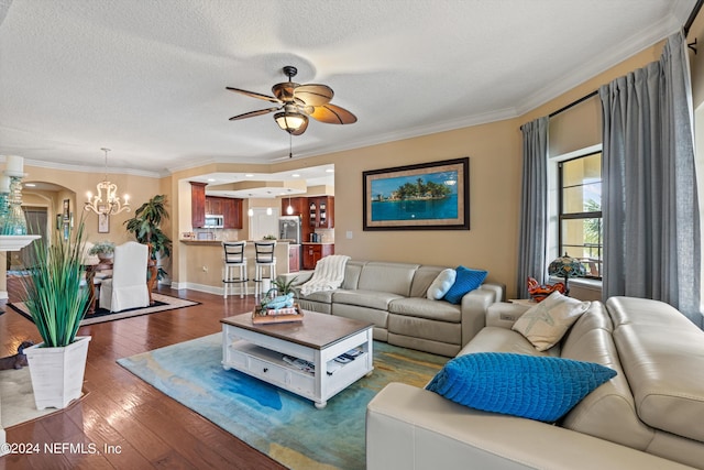 living room with dark hardwood / wood-style flooring, ceiling fan with notable chandelier, a textured ceiling, and ornamental molding