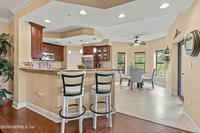 kitchen with ceiling fan, tasteful backsplash, kitchen peninsula, decorative light fixtures, and appliances with stainless steel finishes